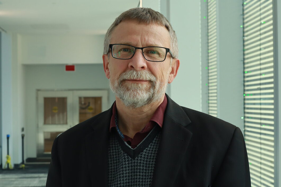 Dr. Istvan Mucsi smiles next to a window while looking at the camera.