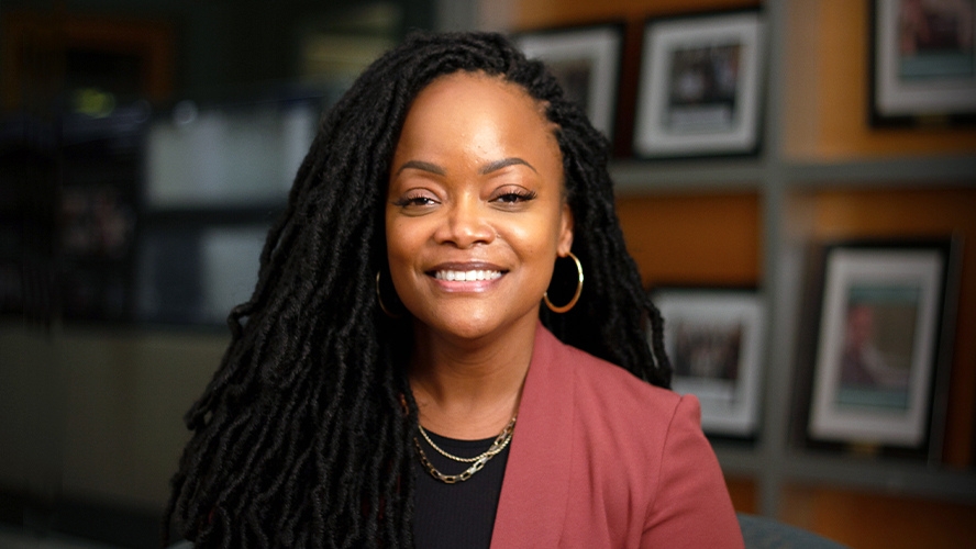Dr. Nicole Woods smiling in front of a wall of photos