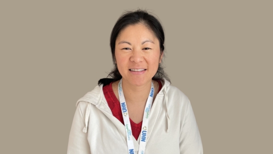 Vanessa Ong with a smile wearing a white hoodie and a lanyard with visible text that reads 