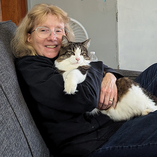 Amy Shannon sitting on her couch with her cat.