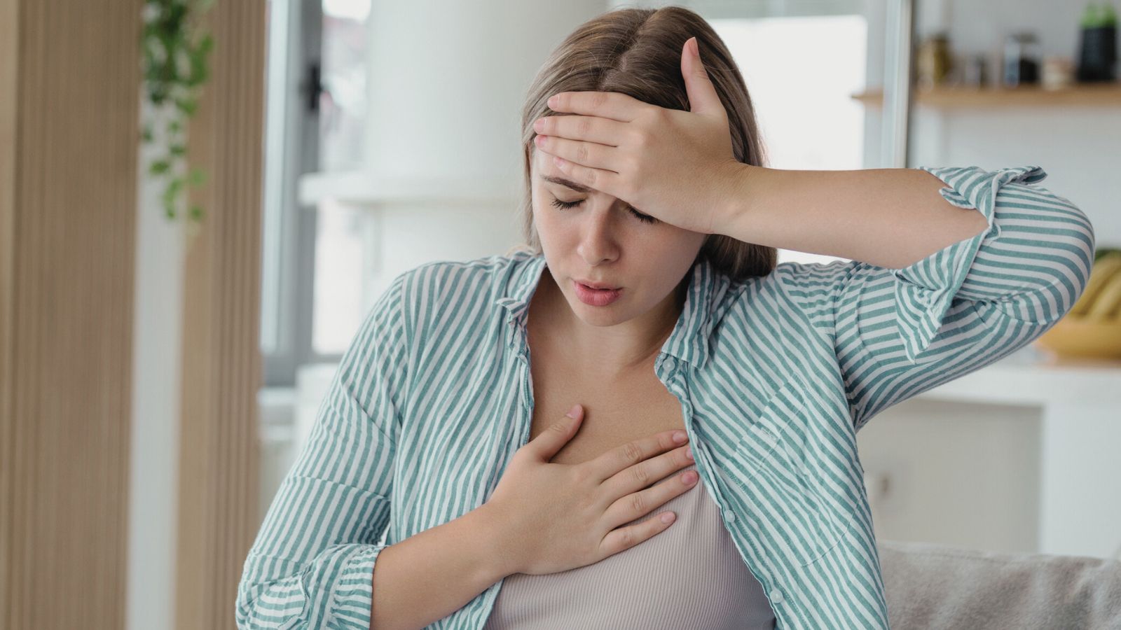 A lady holding her chest and her head with a worried facial expression.