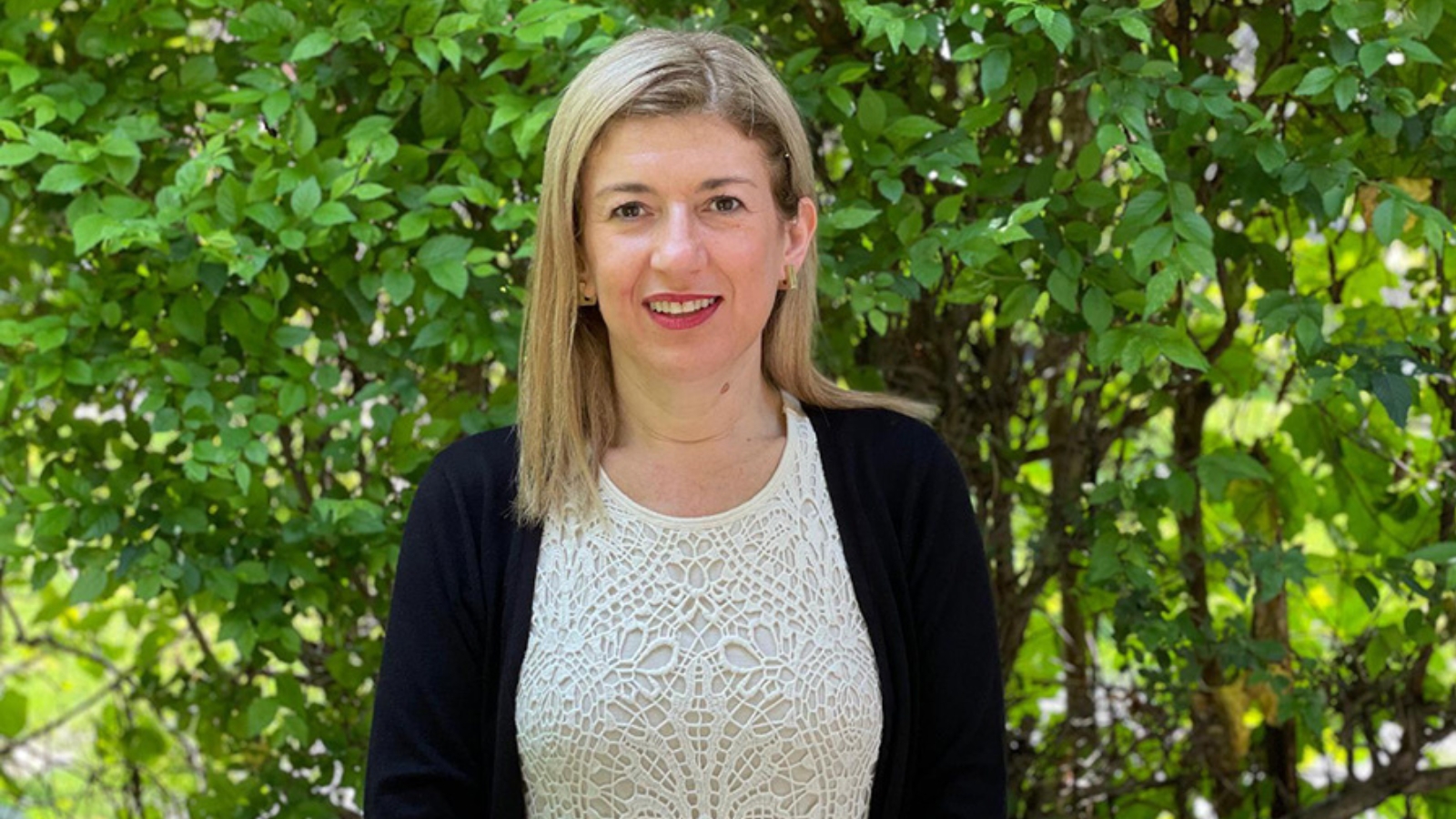 Dr. Monica Daibert-Nido outdoors in front of a tree smiling for the camera