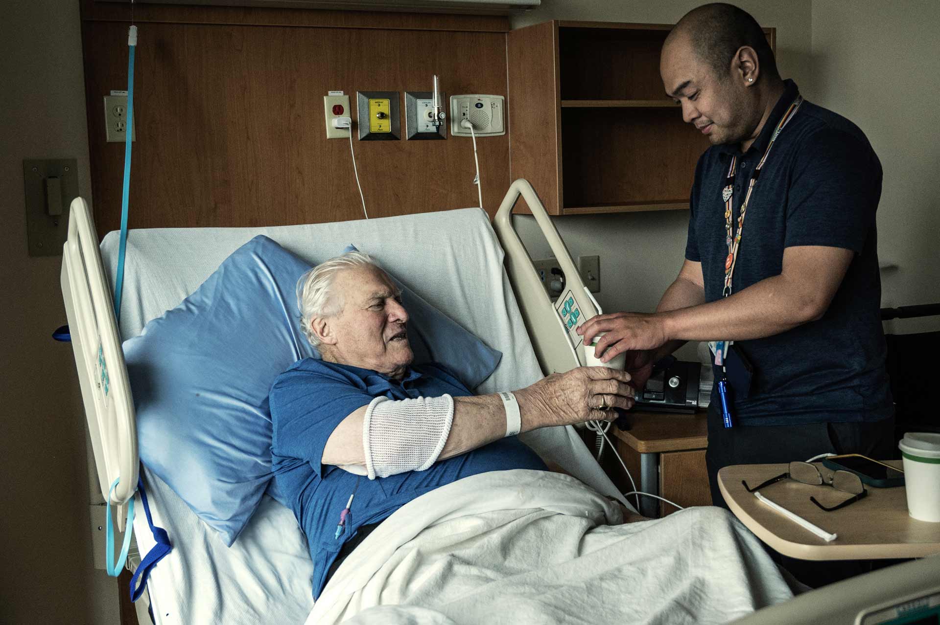 Nurse tending to a patient in hospital bed.