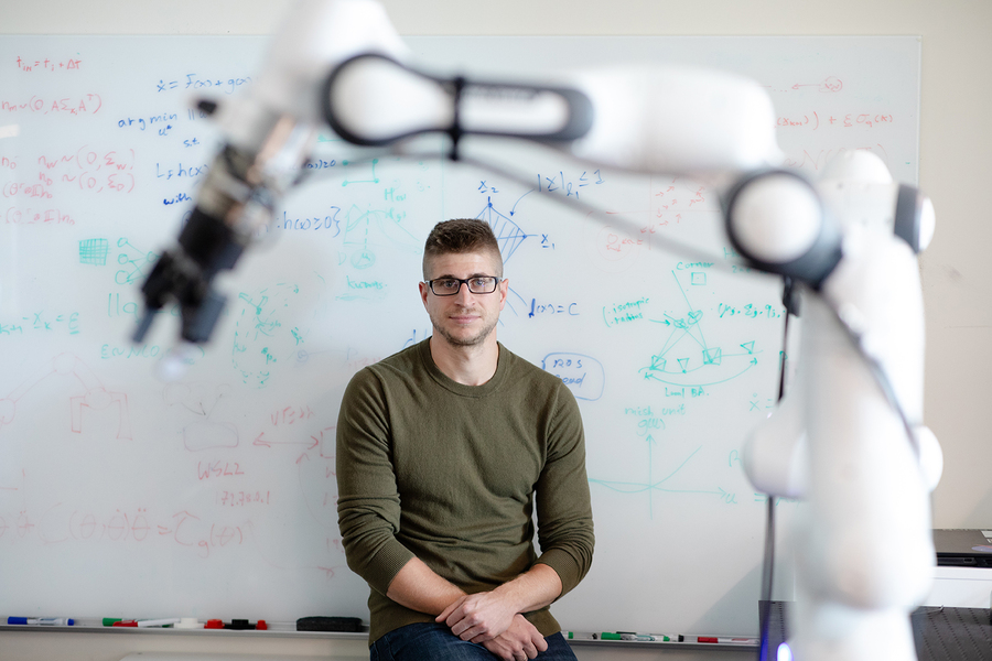 Dr. Brokoslaw Laschowski sitting next to a robot at UHN's KITE Research Institute