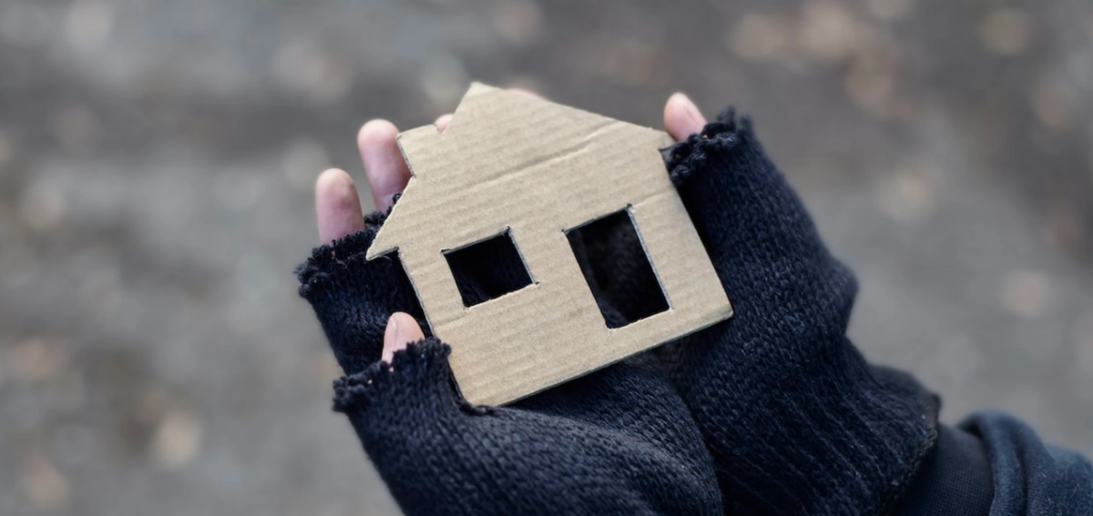 hands holding cardboard cut out of a house