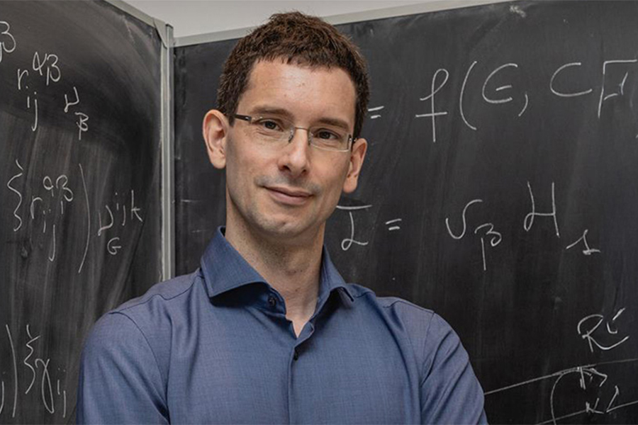 ​Dr. Maurizio De Pittà in front of a chalk board with formulas written on it.