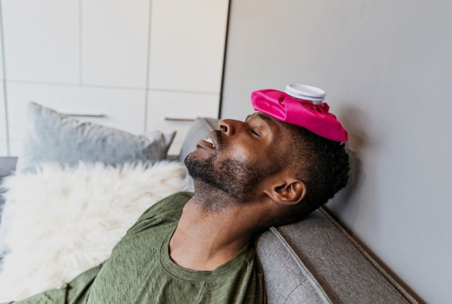 A person with an icepack on their head to combat a migraine